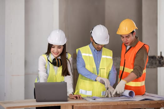 civil engineers meet to plan a construction project and brainstorm ideas about how to work through paper plans and records with laptop