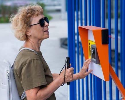 An elderly blind woman reading a text in braille. Button for calling help for people with disabilities