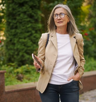 A woman with glasses wearing a tan blazer.