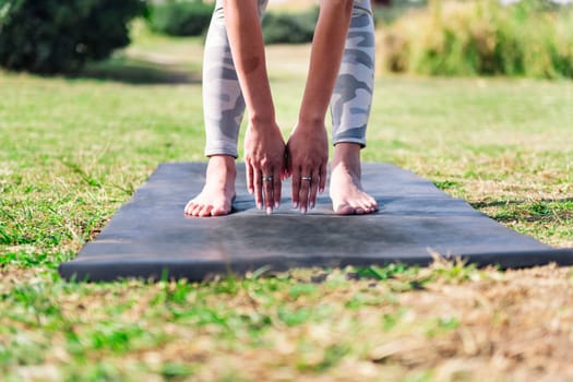 close up detail of hands and feet of a young woman doing stretches on a yoga mat, sport and active lifestyle concept
