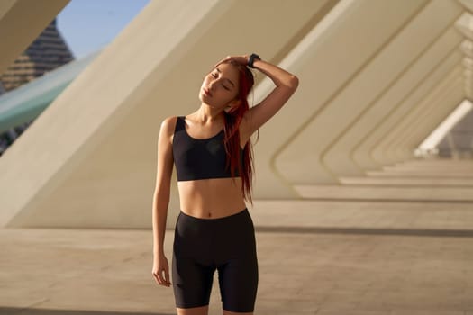 Young sportswoman in tracksuit is stretching outdoor and preparing to jogging. Healthy life concept