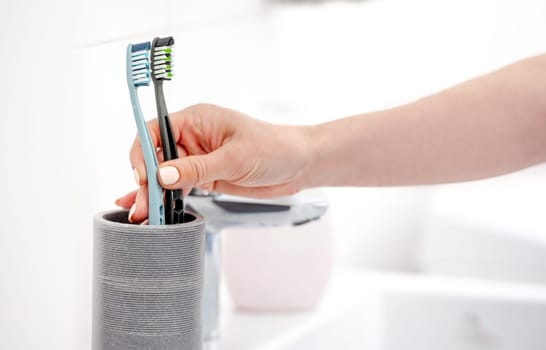 Girl'S Hand Places Two Toothbrushes In Cup, Marking Start Of Couple'S Life Together