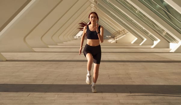 Young sporty female athlete in sportswear running outdoors on a sunny day . Morning jog