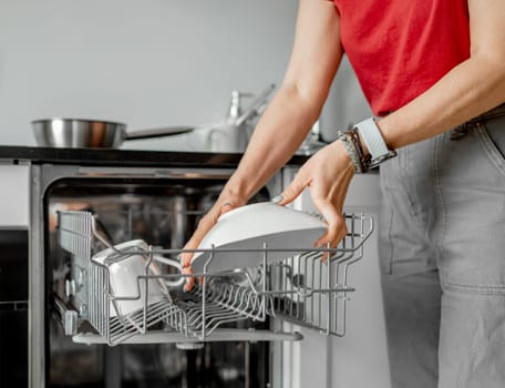 Young Woman Takes Out Clean Dishes From Dishwasher In Close-Up Shot