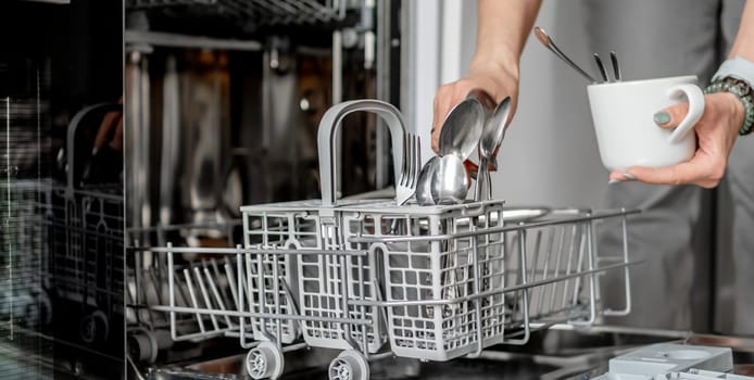 Young Woman Is Loading Spoons Into Dishwasher In Close-Up View