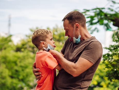 Father and little son hugging, making faces, show a tongue, open mouth, funny plays. Happy childhood.