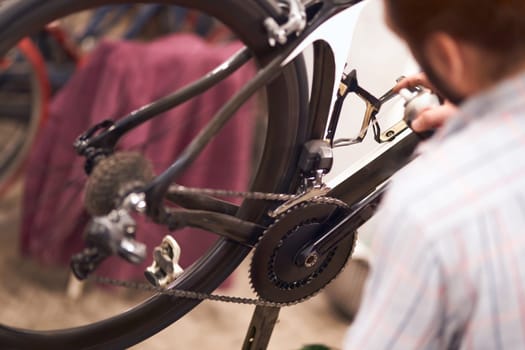 Close up of repairman is lubricate the bike chain in workshop. High quality photo