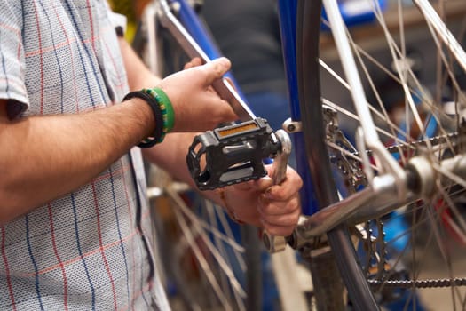 Close up of serviceman repairing modern bike using special tool while working in workshop