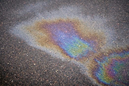 Fuel or oil stain with texture on wet asphalt under rainy conditions, symbolizing environmental pollution