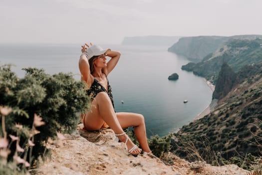 Woman travel sea. Happy tourist taking picture outdoors for memories. Woman traveler looks at the edge of the cliff on the sea bay of mountains, sharing travel adventure journey.