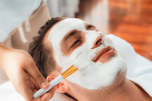 Serene ambiance of spa salon, man customer indulges in rejuvenating with luxurious face cream massage with modern daylight. Facial skin treatment and beauty care concept. Quiescent