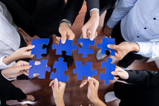 Top view multiethnic business people holding jigsaw pieces and merge them together as effective solution solving teamwork, shared vision and common goal combining diverse talent. Meticulous