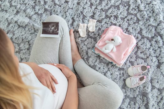 A pregnant woman collects baby things. Selective focus. Home.