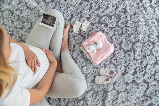 A pregnant woman collects baby things. Selective focus. Home.