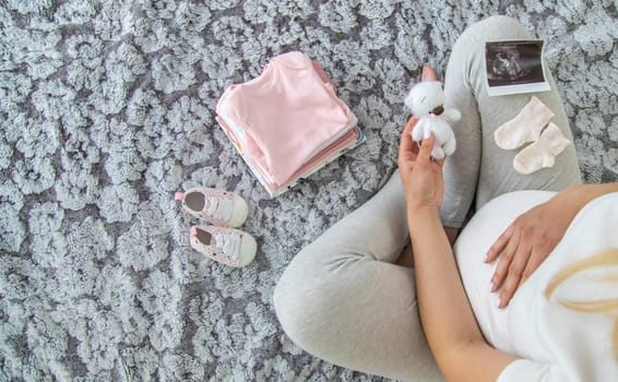 A pregnant woman collects baby things. Selective focus. Home.