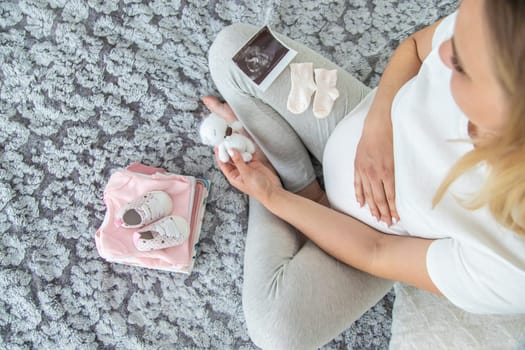 A pregnant woman collects baby things. Selective focus. Home.