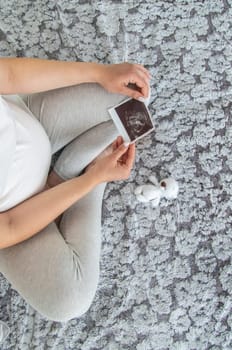 A pregnant woman collects baby things. Selective focus. Home.