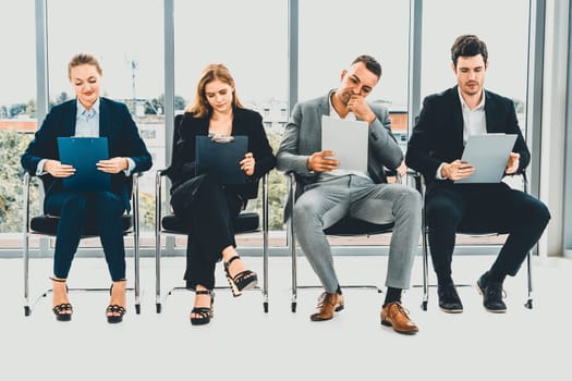 Businesswomen and businessmen holding resume CV folder while waiting on chairs in office for job interview. Corporate business and human resources concept. uds