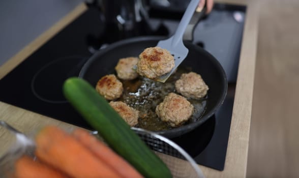 Chef uses spatula to flip over fried cutlets in kitchen closeup. Cooking meat dishes concept.