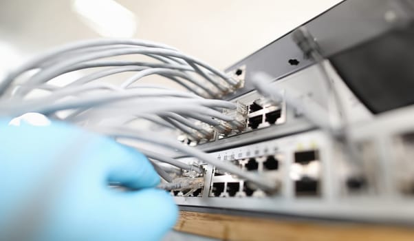 Technician checks the quality of internet connection against background cable hub close-up. Computer bad network cabling concept