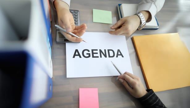 Top view of businessman and businesswoman hands holding pens. Colleagues planning work for future. Order paper and stickers for note on table. Business and agenda concept