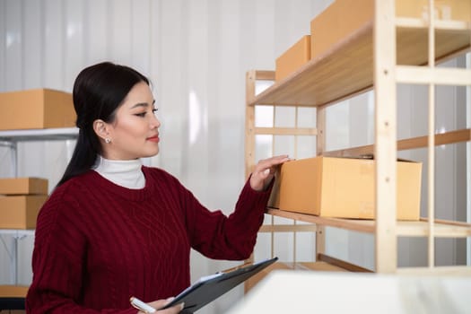 Woman asian in an online store check the customer address and package information on the laptop. Online shopping concept.