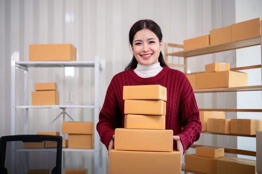 Young business woman asian working online ecommerce shopping at her shop. Young woman sell prepare parcel box of product for deliver to customer. Online selling.