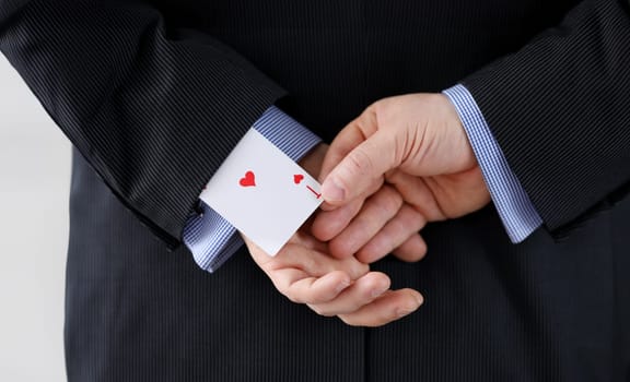 Close up man suit holds ace card behind his back. Identification exposure targets. Mastery methods influence, secrecy influence, preservation illusion. Goal achievement and selfish motives