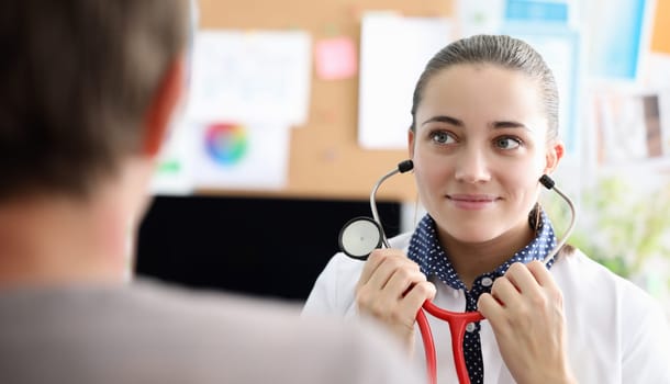 Therapist removes headphones from stethoscope. Doctor will listen to patient, make diagnosis. Drawing up optimal treatment program. Getting adequate treatment. Carefully listen to patient complaints