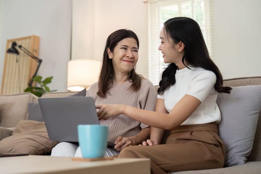 Mother and beautiful young grownup daughter using online app on laptop, watching movie, interactive TV channel. spending leisure time together at home.