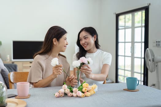 Mother and child arrange flowers together at home on the weekend, family activities, mother and daughter do activities together on Mother's Day.