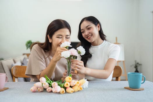 Mother and child arrange flowers together at home on the weekend, family activities, mother and daughter do activities together on Mother's Day.