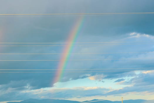 Embark on a visual journey as you capture the stunning beauty of a rainbow set against a backdrop of dramatic clouds