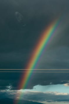 Embark on a visual journey as you capture the stunning beauty of a rainbow set against a backdrop of dramatic clouds