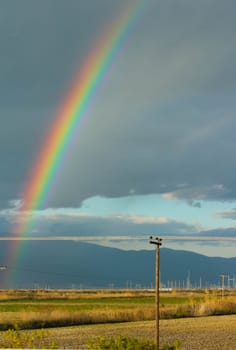 Embark on a visual journey as you capture the stunning beauty of a rainbow set against a backdrop of dramatic clouds