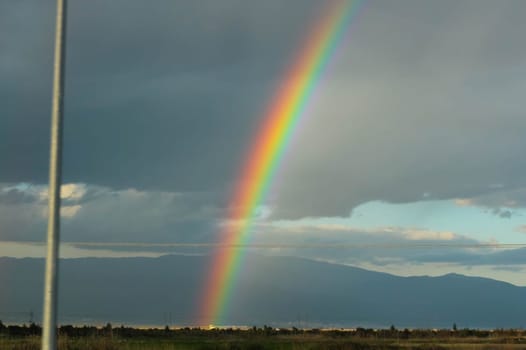 Embark on a visual journey as you capture the stunning beauty of a rainbow set against a backdrop of dramatic clouds