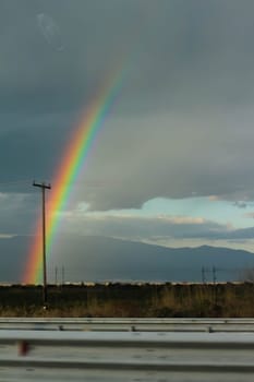 Embark on a visual journey as you capture the stunning beauty of a rainbow set against a backdrop of dramatic clouds