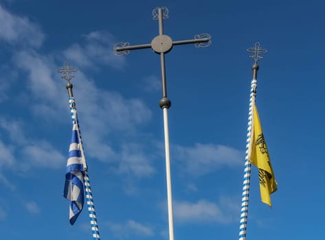 Behold the serene scene of the folded Greek flag, Orthodox flag, and a reverent cross