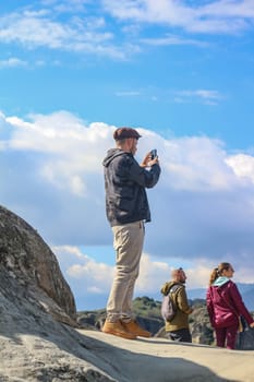 Experience the thrill of adventure as a tourist stands on the edge, gazing over the breathtaking cliffs of Meteora, Greece, on a radiant sunny day