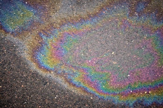 Detailed stain of fuel or oil on wet asphalt during a rainy day, emphasizing environmental pollution.