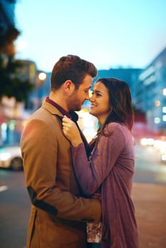 Couple, night and city with hug for love, bonding and romance in relationship with life partner. Happiness, affection and people with commitment and trust, sweet moment and romantic together outdoor.