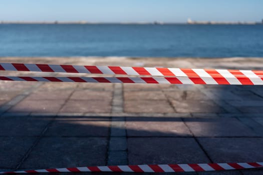 red and white striped rope is laying on the ground. The rope is on a beach near the water