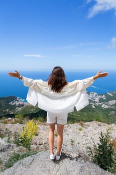 Young beautiful woman stands with her back and looks at the old town of Budva, Montenegro