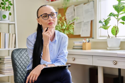 Portrait of female psychotherapist with clipboard at workplace in office. Professional mental therapist, counselor, psychologist, social worker. Health care service psychology psychotherapy treatment