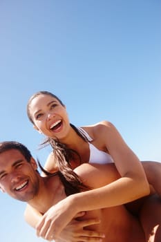 Happy, laughing and couple piggy back at the beach with love, hug and support together on holiday in summer. Joke, sea and vacation with smile and bonding by water with travel in Miami with people.
