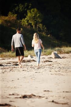 Couple, walking and bonding on outdoor beach sand, peace and travel to nature for holiday. People, back and calm stroll on weekend or vacation, love and date for relationship or marriage and trip.