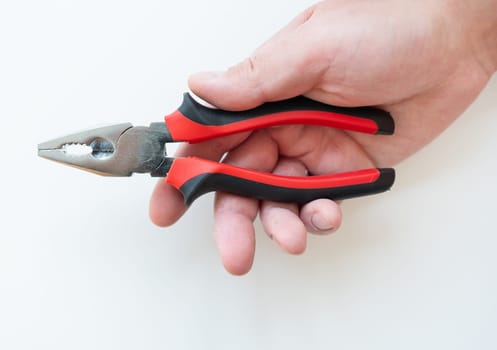 A hand firmly gripping red and black pliers against a white background