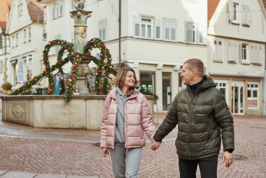 Loving couple of tourists walking around old town. Man woman couple walking europe old town Germany. Couple of lovers leisurely stroll in the cool autumn morning on the streets of a BIETIGHEIM-BISSINGEN (Germany). The guy holds his wife. Vacation, autumn, holiday. Couple Walking in Europe's Old Town