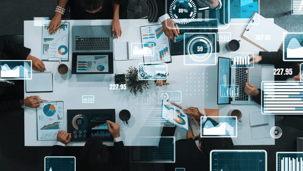 Top down aerial view of business people discussing about financial strategy on table with document and tablet display investment statistic at meeting. Diverse team brainstorm about plan. Directorate.