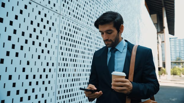 Smart manager looking at mobile phone and walking at street while wearing suit. Skilled investor looking mobile phone to checking sales or working while holding coffee cup. White background. Exultant.